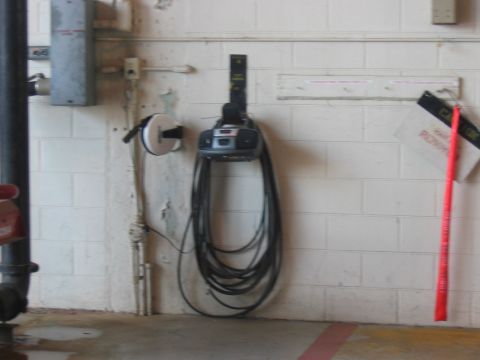 1988 Ford Bronco - A utility area with a hose reel mounted on a concrete block wall.