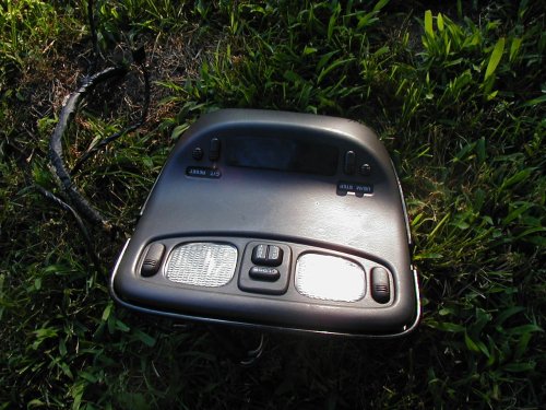 Gray automotive overhead console with map lights lying on grass