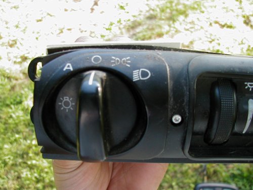 Black rotary headlight switch panel held in hand outdoors