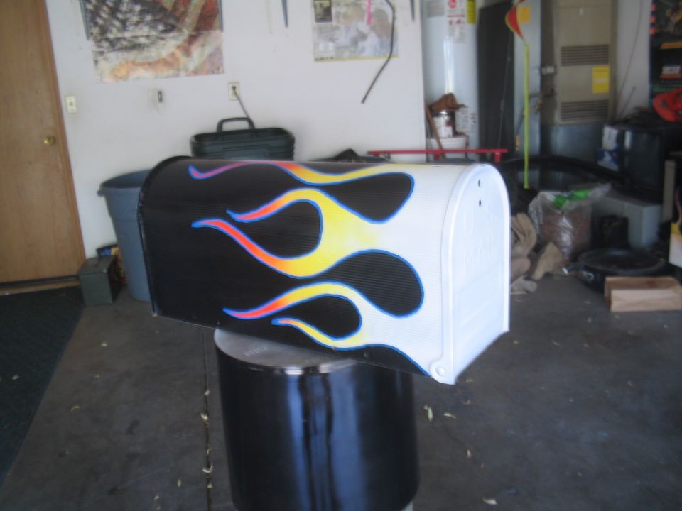 White mailbox custom airbrushed with orange and blue hot-rod flames in a garage