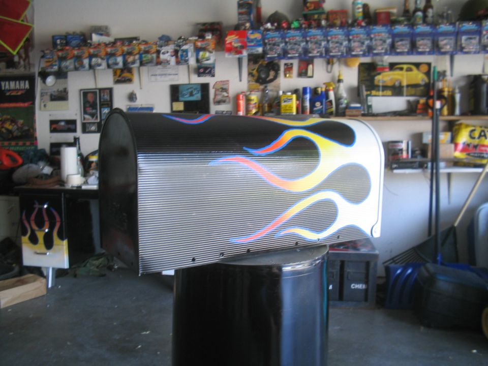 Mailbox custom-painted with hot-rod flames on a black post in a garage