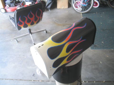 1981 Ford Bronco - A car fender with custom flame paintwork is displayed on a stand in a garage setting.