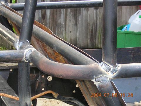 1984 Chevrolet Blazer - Welded roll cage tubing is visible on a vehicle frame, with a wooden fence in the background.