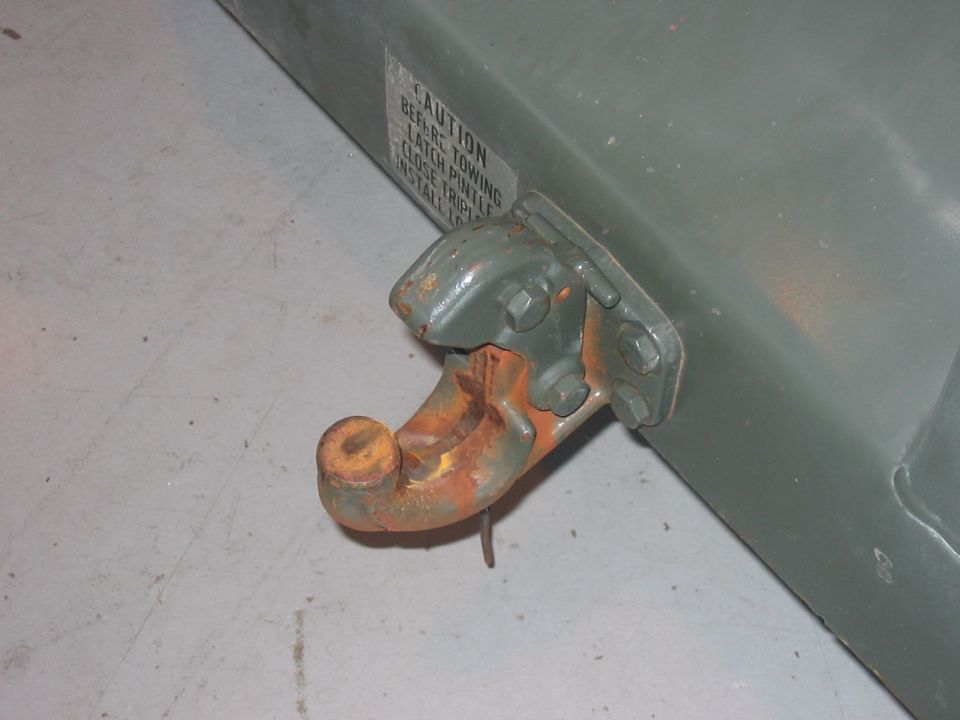 Green tow hitch with rust on the hook and latch mechanism. A caution label is visible on the side