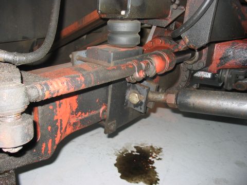 1988 Ford Bronco - Close-up view of the front suspension and steering components, showing an oil leak on the floor.