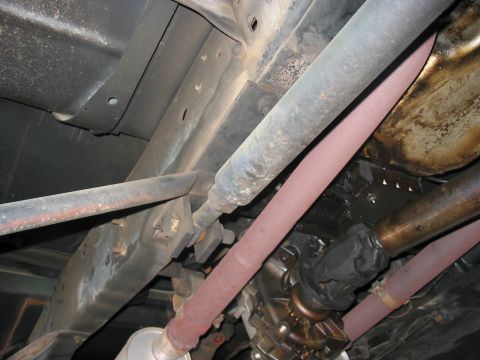1988 Ford Bronco - The underside of a vehicle shows the drivetrain components and exhaust system, with some signs of wear and tear.