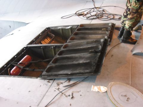 1988 Ford Bronco - Close-up of an open aircraft access panel revealing internal wiring and a red cylindrical object.