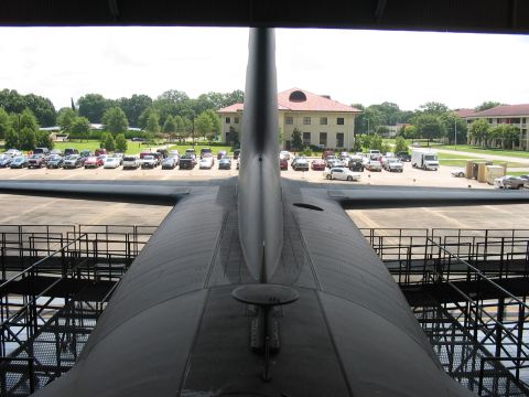 1988 Ford Bronco - Looking out from the tail of a large aircraft at a parking lot filled with cars and a building in the background.