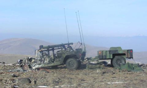 1981 Ford Bronco - A damaged military vehicle is hitched to a camouflage trailer in a barren, outdoor landscape.