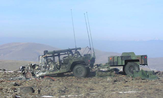 Damaged military vehicle and trailer on a desolate hillside