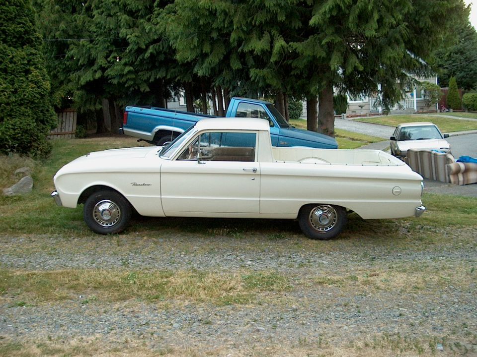 White Ford Falcon Ranchero parked side-on on gravel, blue pickup behind under trees