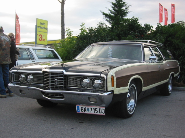 Station wagon with wood paneling, chrome bumper, and whitewall tires, parked outdoors