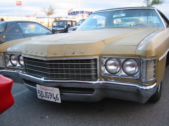 Gold Chevrolet sedan front end with chrome grille and dual headlights. California license plate 5DJG946