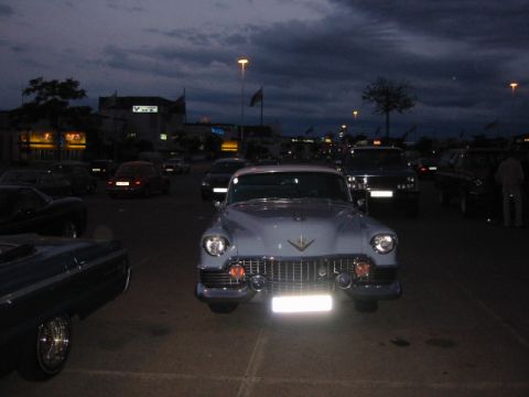 1992 Ford Crown Victoria - A classic Cadillac is parked in a lot as the sky darkens, with other vehicles visible in the background.