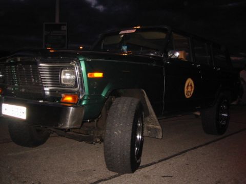 1992 Ford Crown Victoria - A dark green SUV with a prominent grille and large tires is parked at night.