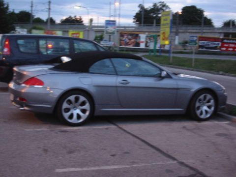 1992 Ford Crown Victoria - A silver convertible is parked next to a dark SUV.