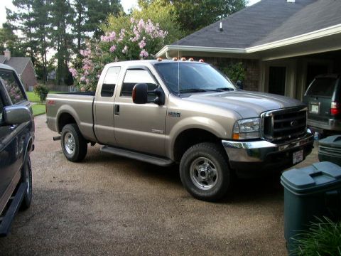 1995 Ford Bronco - Tan Ford F-250 Super Duty pickup truck parked in a driveway.