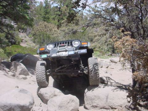 1988 Ford Bronco - A black Jeep Wrangler navigates a challenging rocky trail.