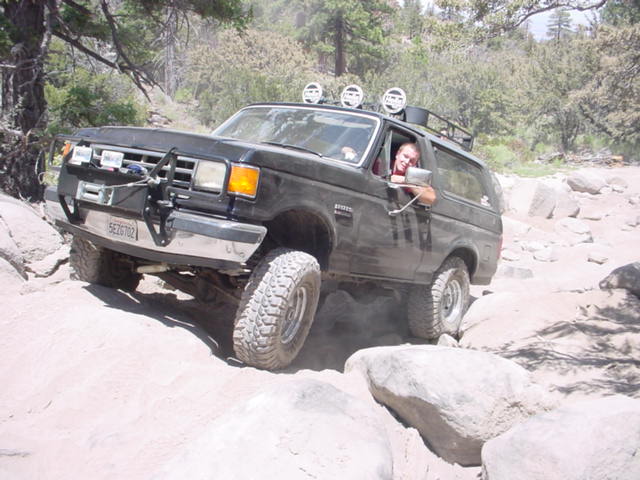 Black 1988 Ford Bronco navigating a rocky off-road trail with a person inside