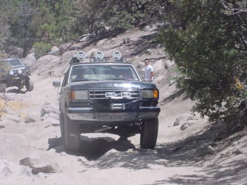 1988 Ford Bronco - Two 4x4 vehicles navigate a challenging rocky trail in a mountainous area.
