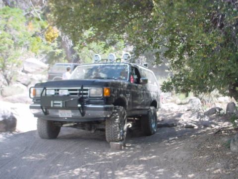 1988 Ford Bronco - A modified black Ford Bronco navigates a rocky trail with another vehicle visible in the background.