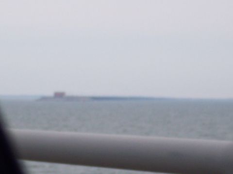 1990 Ford Bronco - A hazy view over water shows a distant structure, with a blurred foreground element.