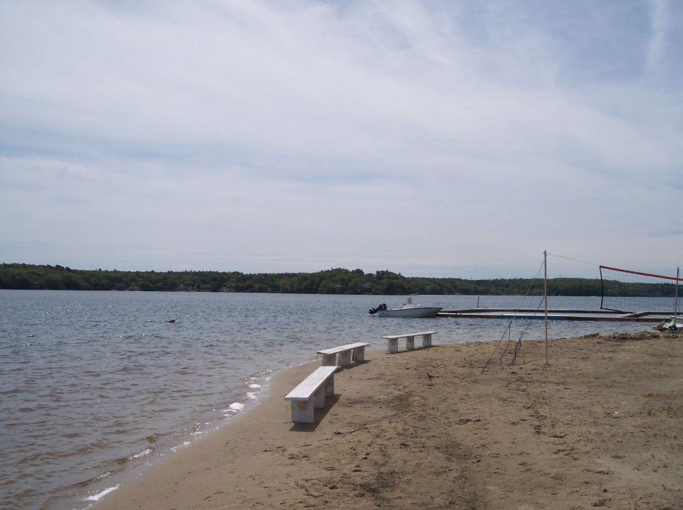 White boat docked on a lake with a sandy beach and benches