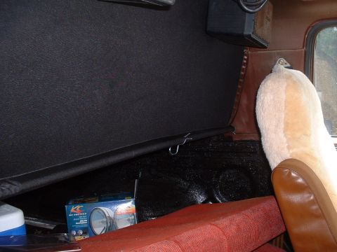 1982 Ford Bronco - Interior view of a vehicle showing red seats, a sheepskin cover, and a box of KC headlights on the floor.