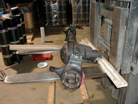 1983 Ford Bronco - A Ford rear axle assembly is being handled by a forklift in a warehouse setting.