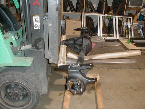 1983 Ford Bronco - A forklift is used to move a vehicle axle assembly, which is resting on wooden planks.