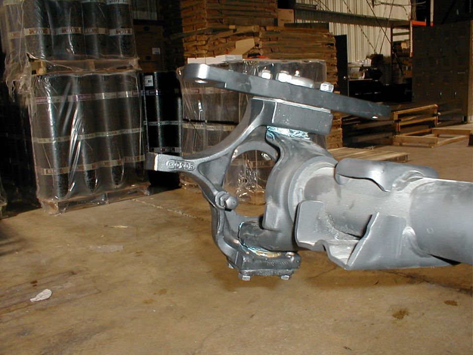Gray metal suspension part with "C9203" stamped on it, in a warehouse