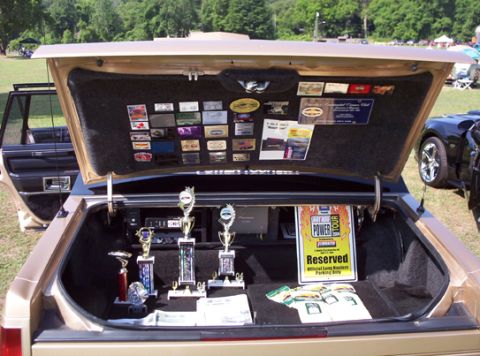 1991 Ford Crown Victoria LTD - The trunk of a car is open, displaying several trophies and a sign for the 'Hot Rod Power Tour'.