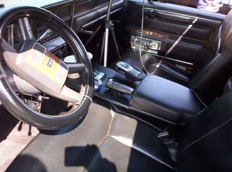 1991 Ford Crown Victoria LTD - Interior view of a black car, showing the steering wheel, dashboard, and center console with two cell phones.