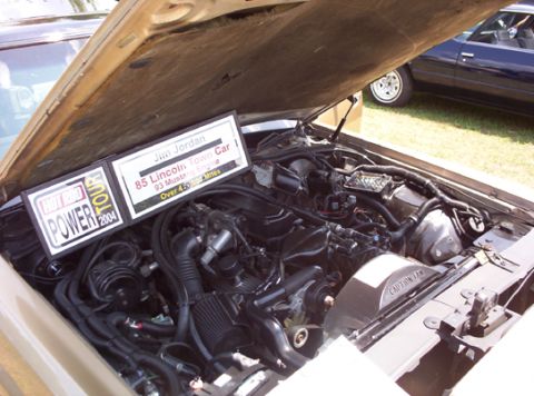1991 Ford Crown Victoria LTD - The engine bay of a car is shown, with a sign indicating it's an '85 Lincoln Town Car with a '93 Mustang Engine'.