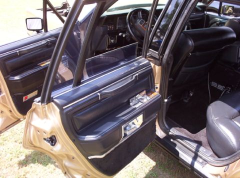 1991 Ford Crown Victoria LTD - The interior of a car is shown with the driver's side door open, revealing black leather seats and the dashboard.