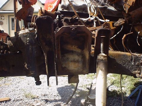 1988 Ford Bronco - Close-up view of severely damaged and burnt vehicle chassis and engine components.