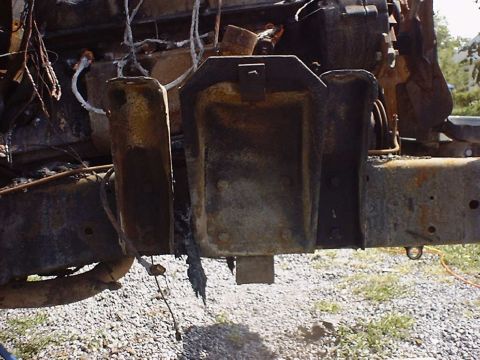 1988 Ford Bronco - Close-up of a heavily damaged and burnt vehicle frame and engine components.
