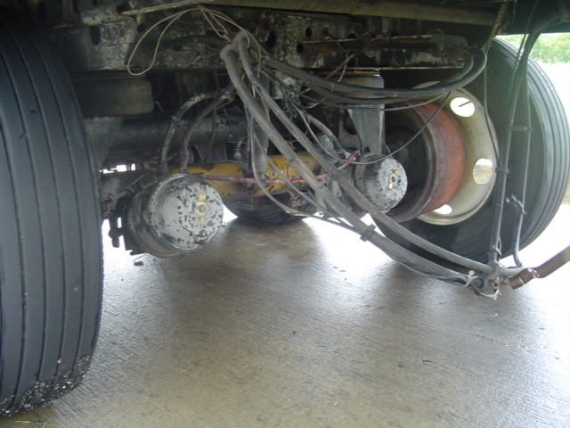 Truck rear axle with dual wheels, brake drums, and air lines. The suspension components are visible