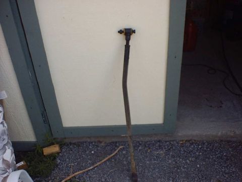 1988 Ford Bronco - Steering linkage rod shown leaning against a wall outdoors.