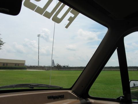 1988 Ford Bronco - View from inside a vehicle shows an airport tarmac with a cargo plane under a cloudy sky.