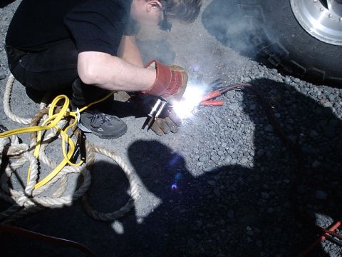 1996 Ford Bronco - A person is welding a part of a vehicle, with sparks and smoke visible.