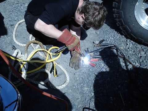 1996 Ford Bronco - A person in work gloves is welding, with a vehicle tire visible in the background.