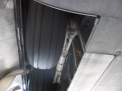 1988 Ford Bronco - Close-up view of an airplane's landing gear and tire, showing the complex mechanical components and riveted metal construction.
