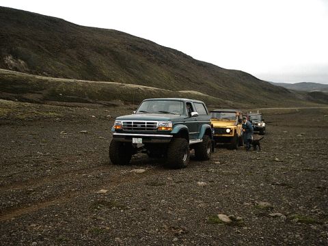 1996 Ford Bronco - Several off-road vehicles, including a 1996 Ford Bronco, are parked on a rocky, barren landscape.