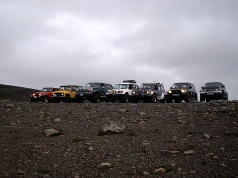 1996 Ford Bronco - A convoy of SUVs is parked on a rocky terrain, with a cloudy sky overhead.