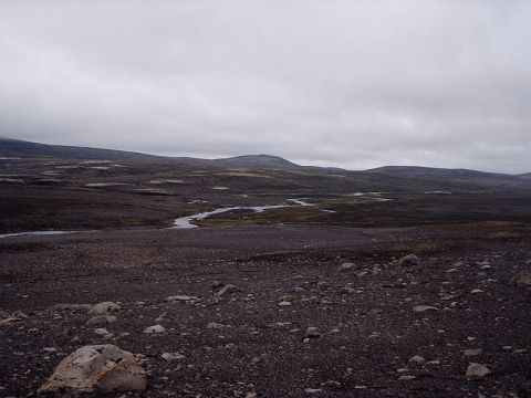 1996 Ford Bronco - A wide view of a desolate, rocky terrain with a river flowing through it under a cloudy sky.