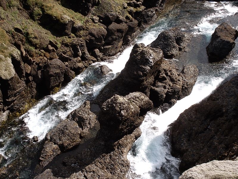 Whitewater rapids flowing over dark rocks in a rocky ravine
