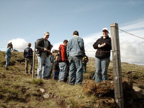 1996 Ford Bronco - People gathered on a hill, with a wooden fence post and barbed wire in the foreground.