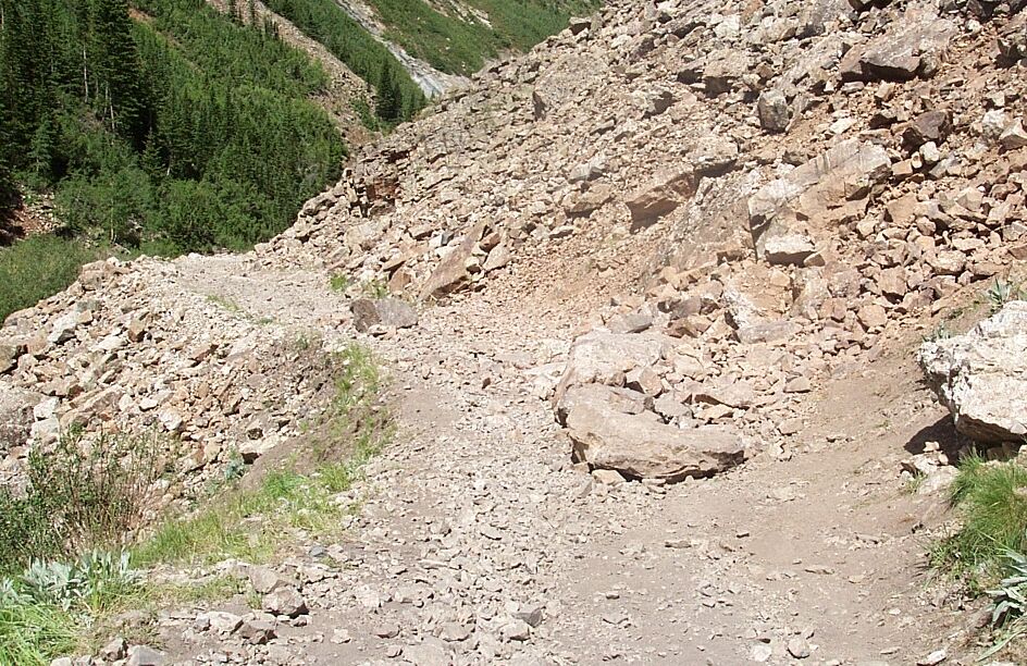 Rocky mountain trail with loose rocks and sparse vegetation