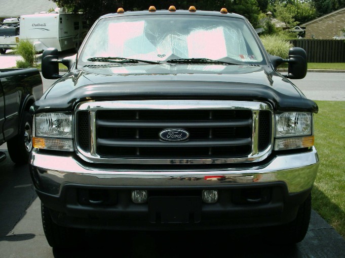 Front of a black Ford Super Duty with cab marker lights, chrome grille in a driveway